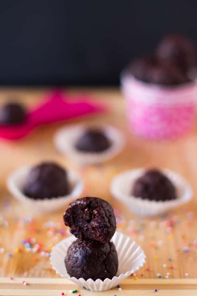 Brownie bites in paper cups on a wood board.