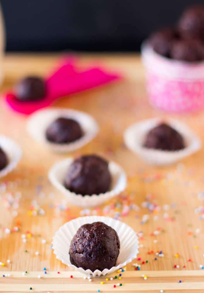  Brownie Bites on a wood table in paper cups.