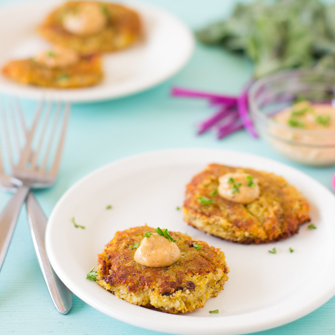 Fritters on white plates on a blue table top.