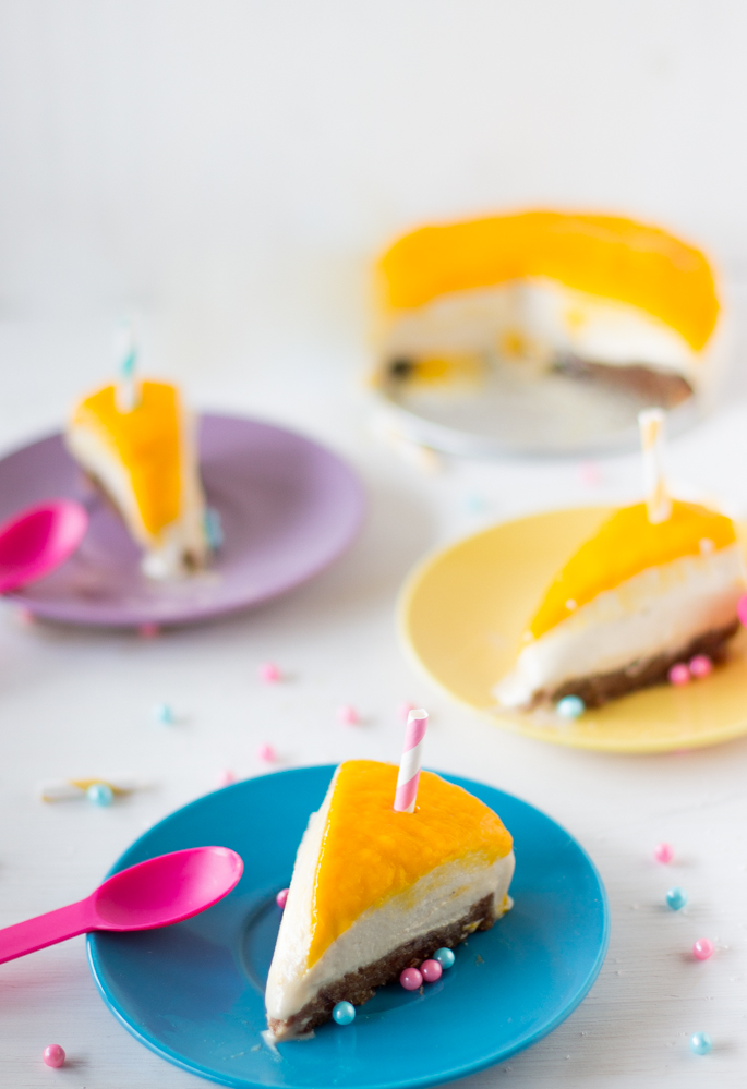 Slices of vegan mango coconut cheesecake on colored plates. 