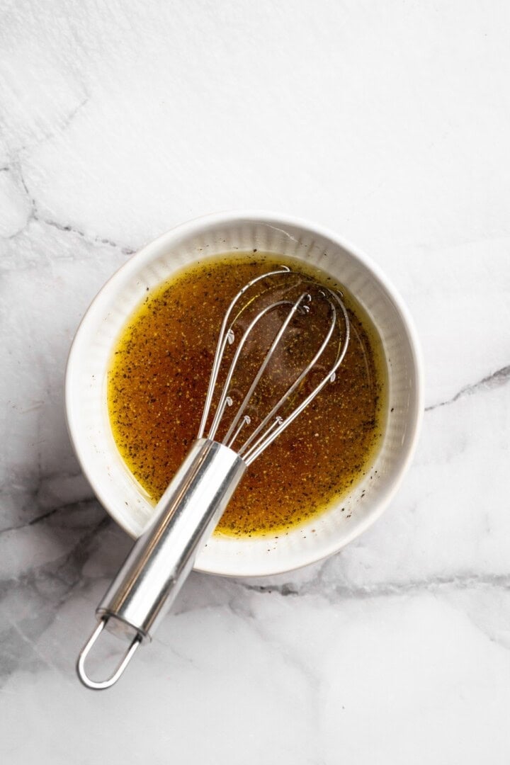 Overhead view of maple apple vinaigrette in small bowl with whisk