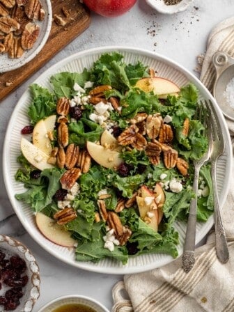 Overhead view of apple, pecan, and vegan feta salad on plate with two forks