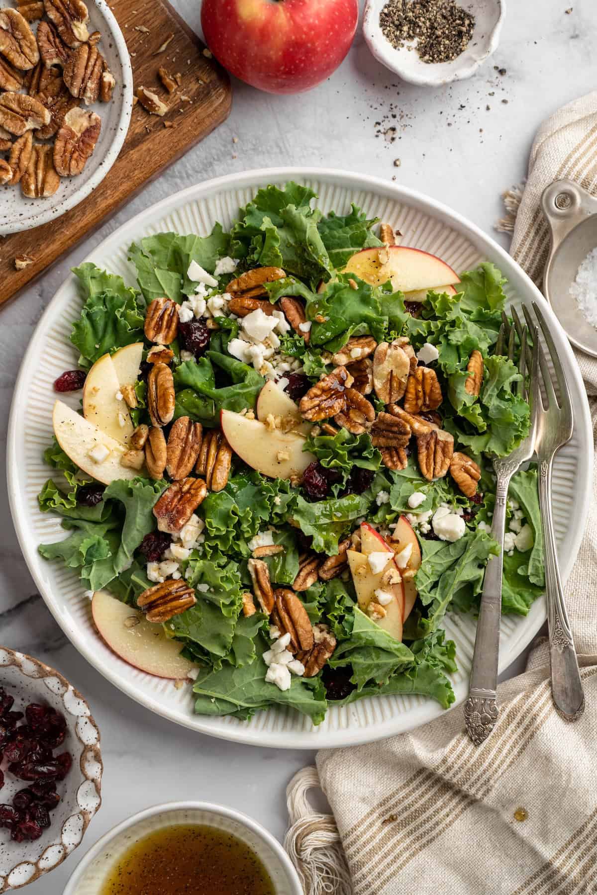 Overhead view of apple, pecan, and vegan feta salad on plate with two forks