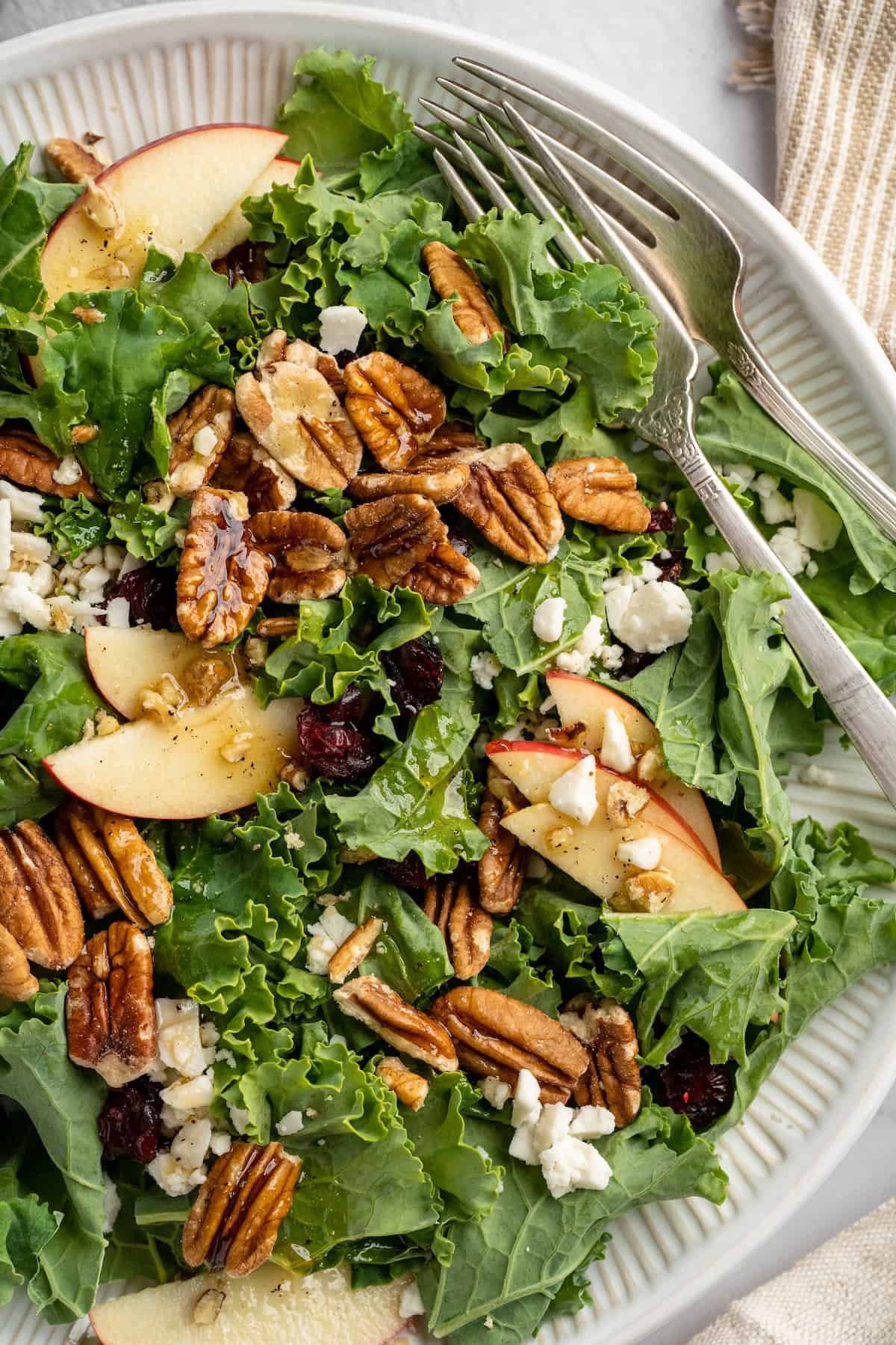 Plate with apple, pecan, and vegan feta salad and two forks