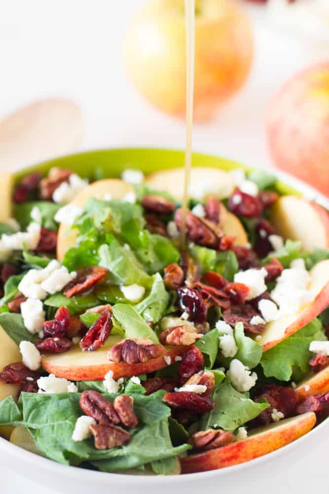 Dressing being poured on apple pecan salad.