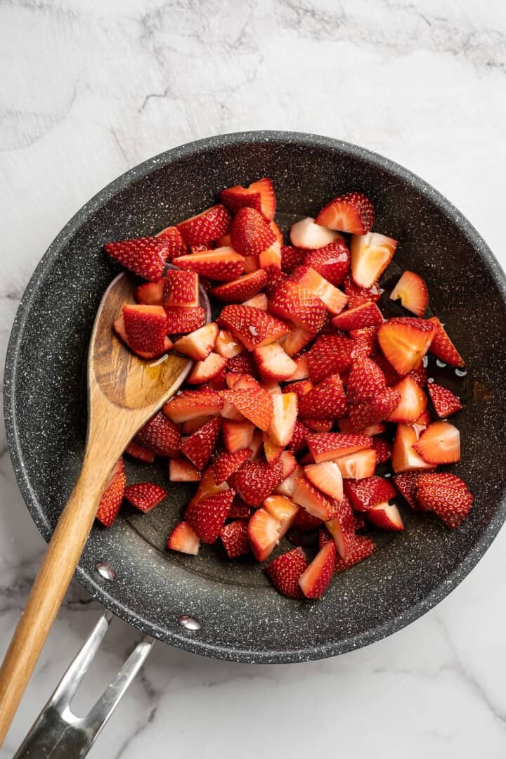 Overhead view of strawberries in skillet with lemon juice and maple syrup