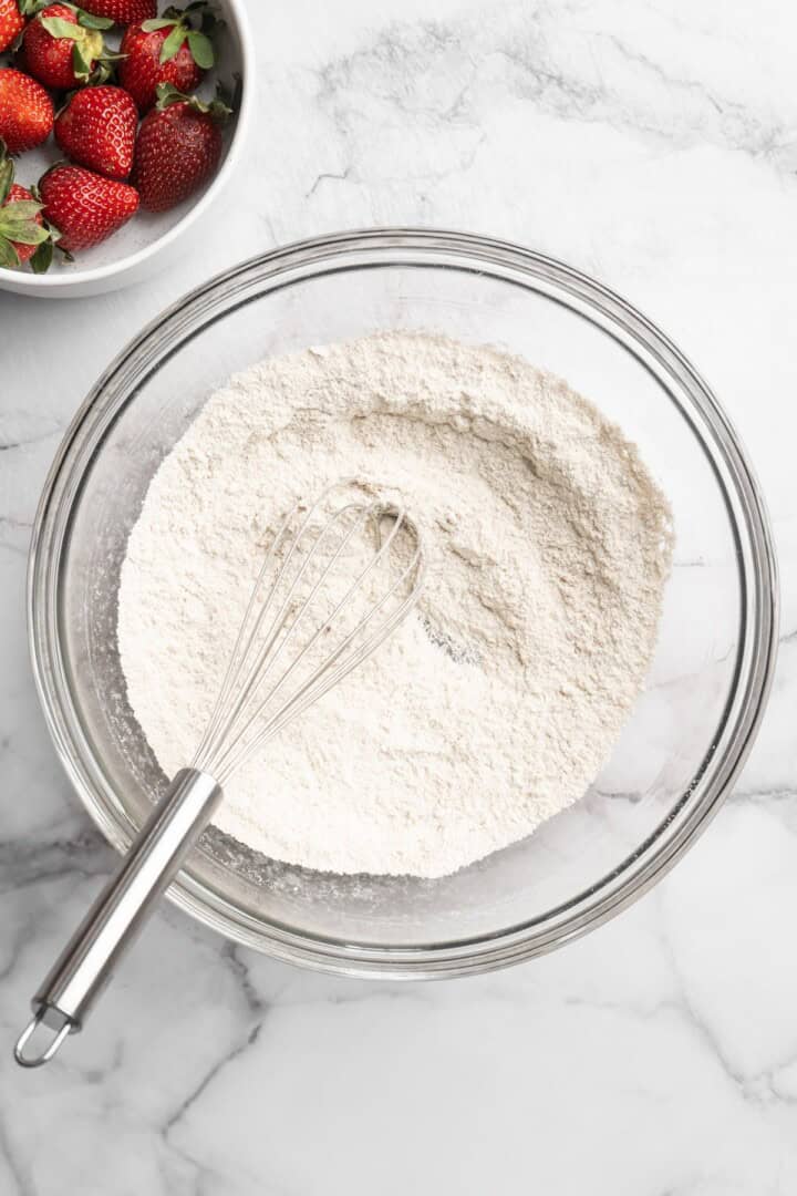 Overhead view of dry ingredients for peanut butter waffles in bowl with whisk