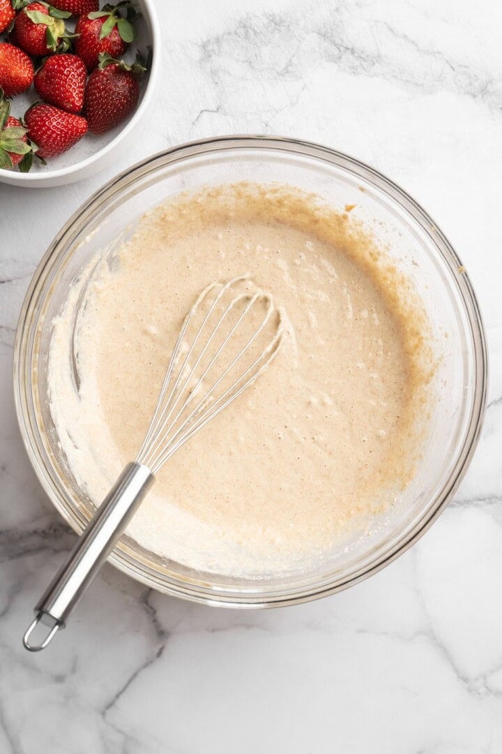 Overhead view of peanut butter waffle batter in bowl with whisk