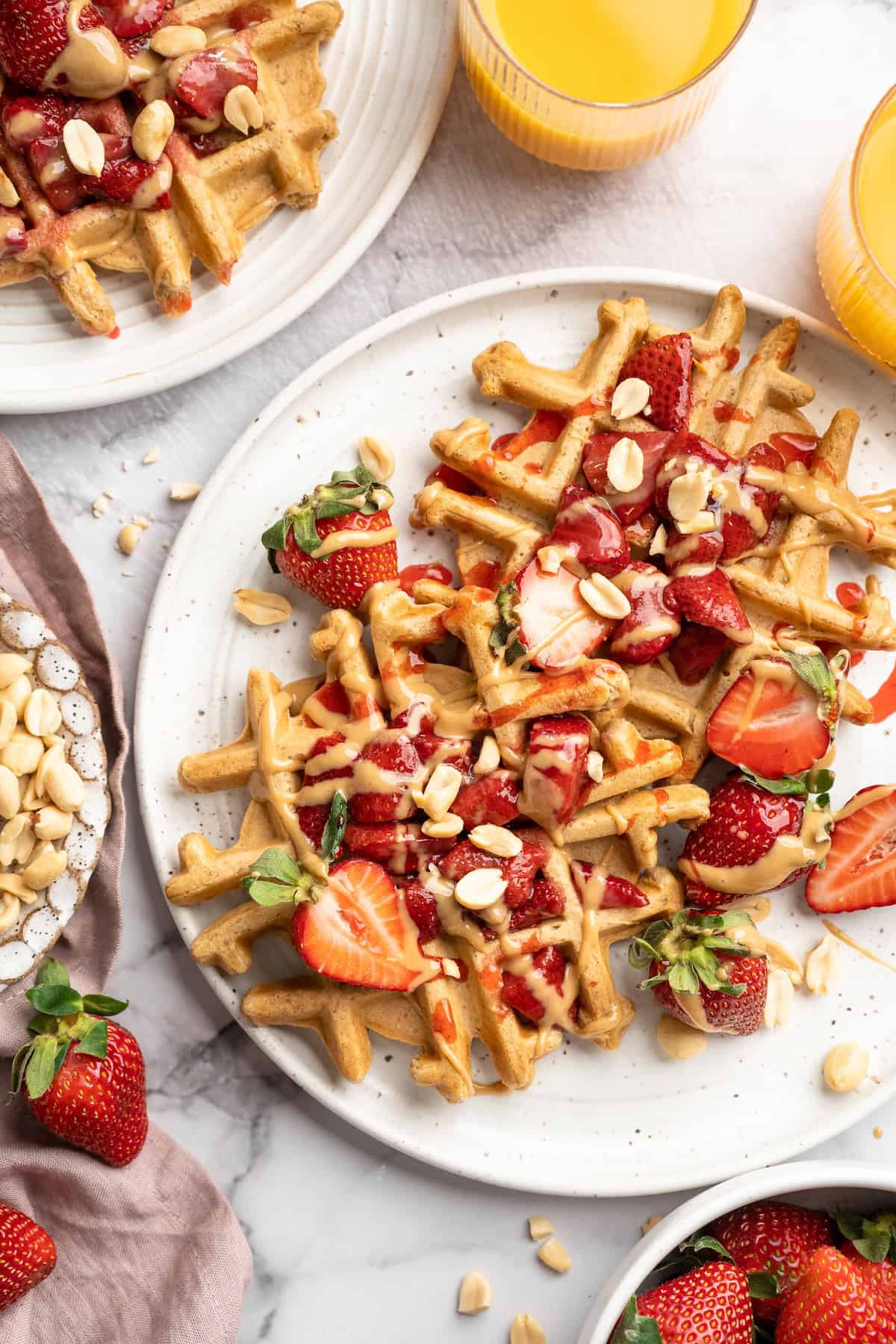 Overhead view of peanut butter waffles on plate with strawberry jelly compote and fresh berries