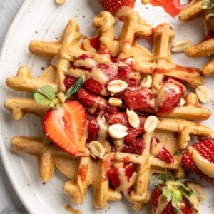 Overhead view of peanut butter and jelly waffles on plate with fresh strawberries