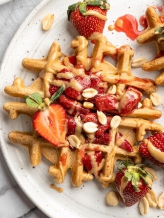 Overhead view of peanut butter and jelly waffles on plate with fresh strawberries