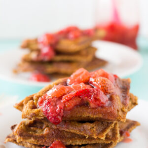 A pile of peanut butter waffles on a white plate.