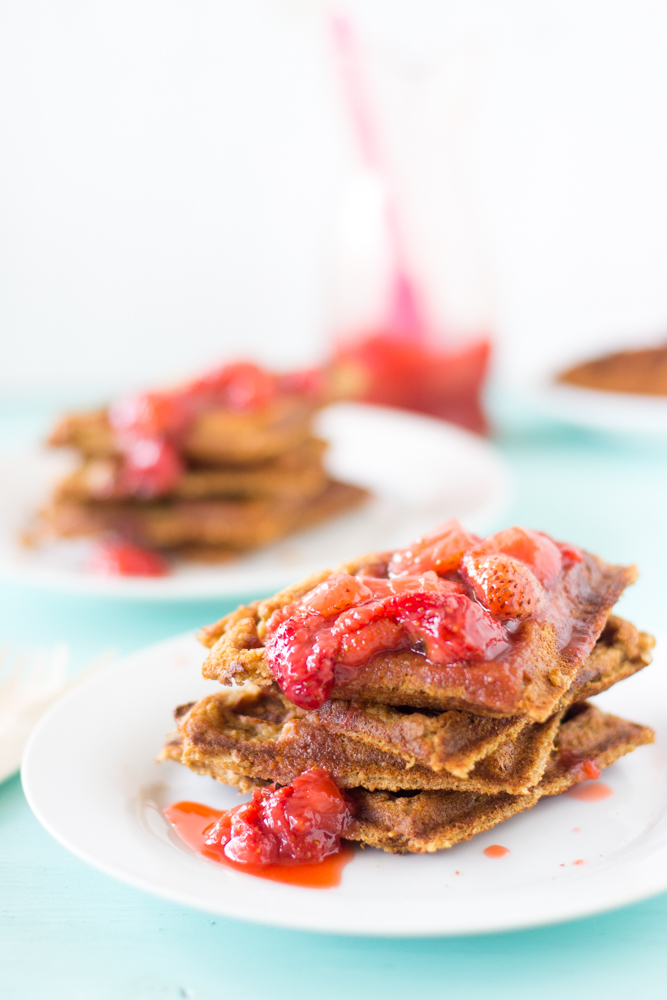 A stack of waffles with compote on a white plate.