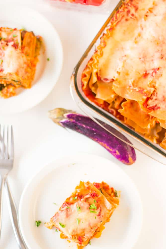 Top down shot of lasagna in a baking dish with slices on plates. 