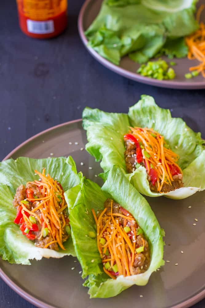 Three lettuce wraps on a grey plate.