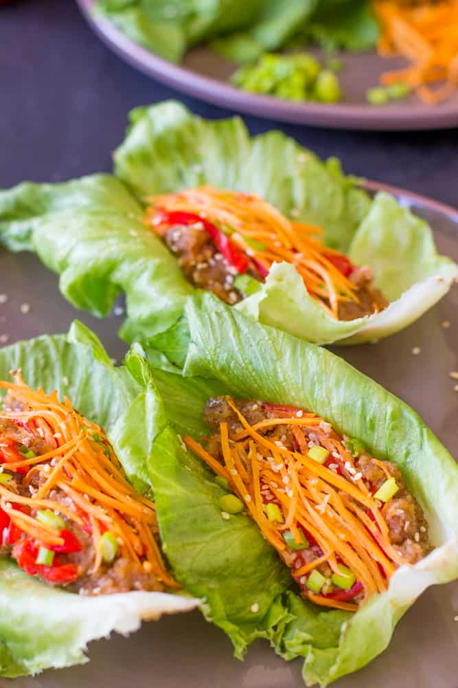 Three vegan asian lettuce wraps on a grey dish.