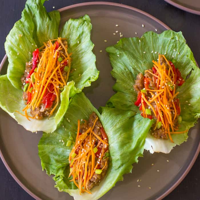 Top down view of three lettuce wraps on a grey plate. 