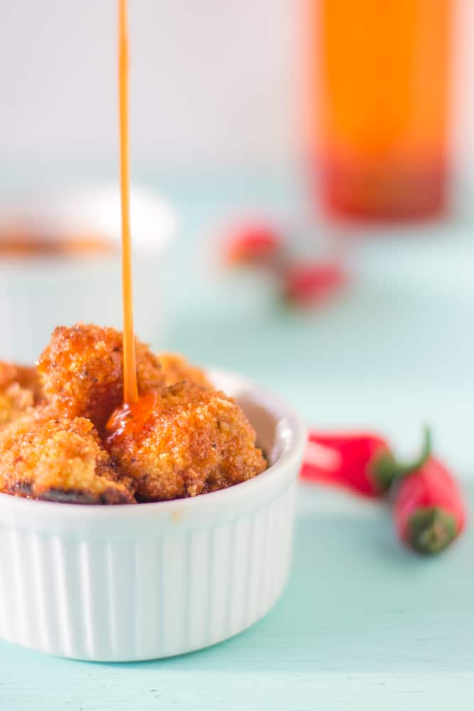 Cauliflower bites in a white ramekin with sauce drizzling on top. 