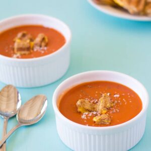 Two white bowls of tomato soup.