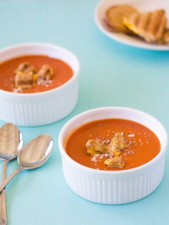 Two white bowls of tomato soup.