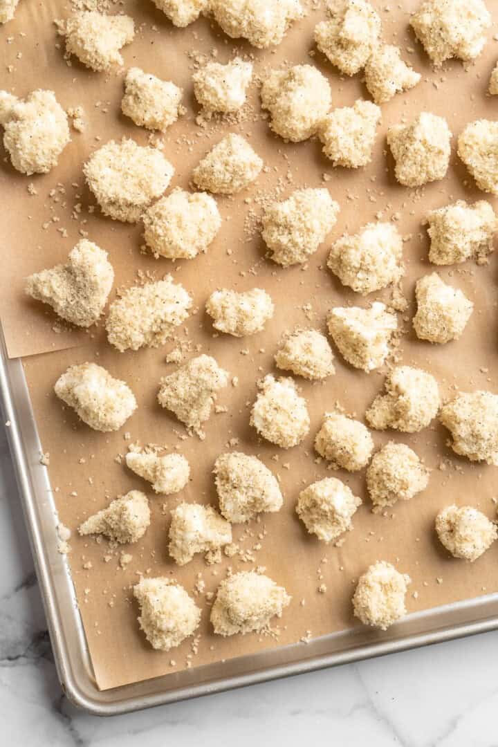 These Cauliflower Bites are crispy, crunchy and full of big flavour thanks to an irresistible sweet sriracha sauce. A total crowd pleaser! Overhead view of unbaked cauliflower bites on sheet pan