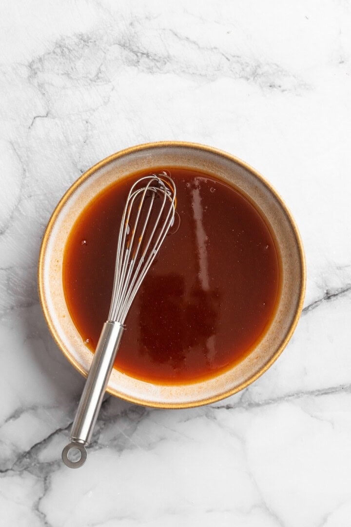 These Cauliflower Bites are crispy, crunchy and full of big flavour thanks to an irresistible sweet sriracha sauce. A total crowd pleaser! Overhead view of sweet sriracha sauce in bowl with whisk