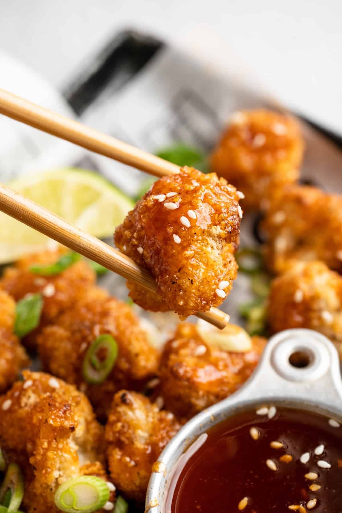These Cauliflower Bites are crispy, crunchy and full of big flavour thanks to an irresistible sweet sriracha sauce. A total crowd pleaser! Chopsticks picking up cauliflower bite