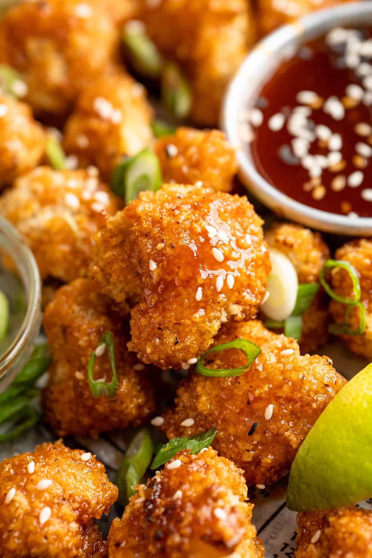 These Cauliflower Bites are crispy, crunchy and full of big flavour thanks to an irresistible sweet sriracha sauce. A total crowd pleaser! Closeup of crispy cauliflower bite with sweet sriracha sauce