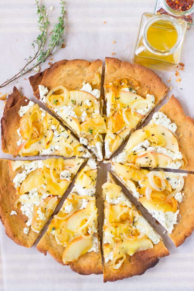 Overhead shot of sliced goat cheese pizza with olive oil on the side. 