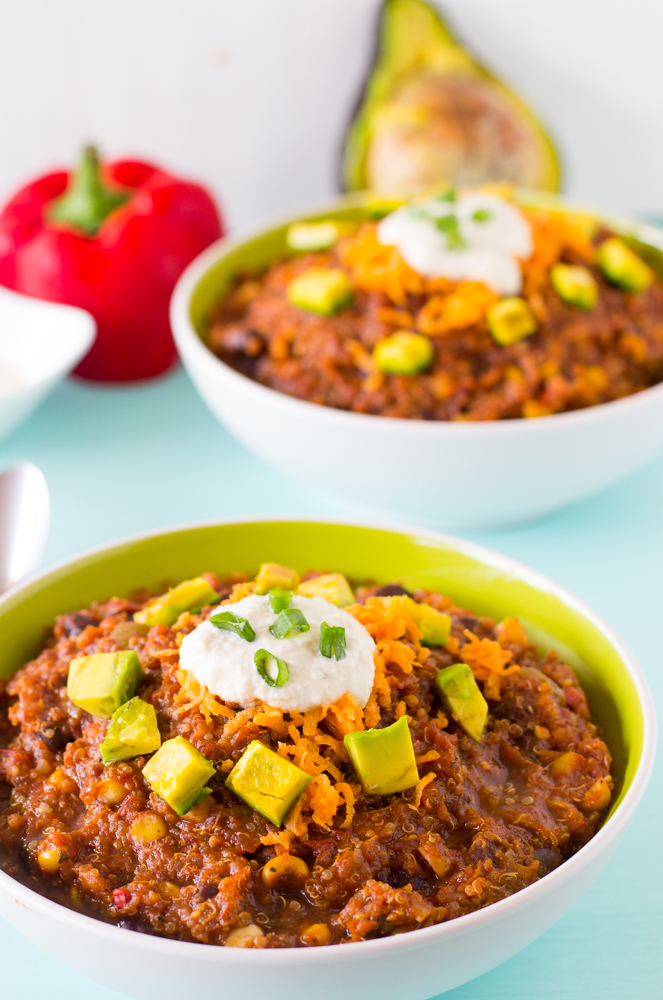 Chili in a green and white bowl with diced avocado.