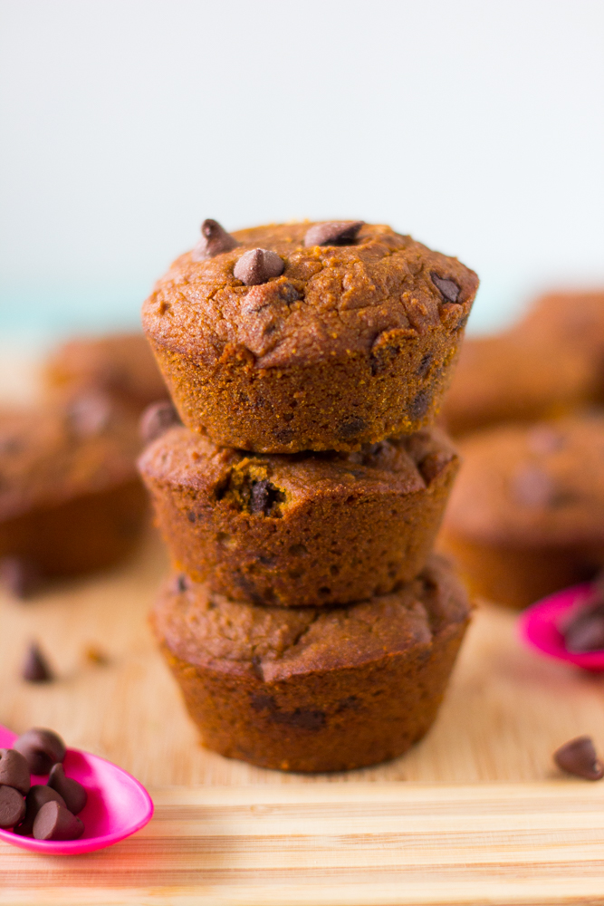 A stack of three pumpkin muffins on wooden table top. 