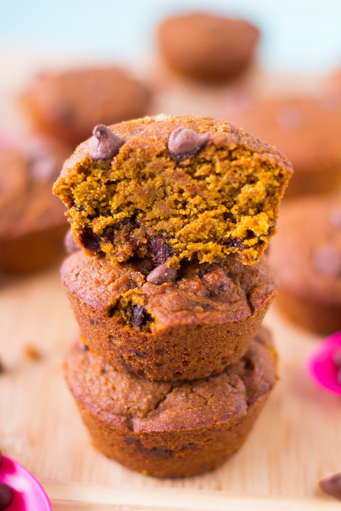 A stack of vegan pumpkin chocolate chip muffins on a wood board. 