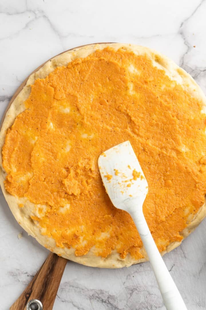 Spreading sweet potato sauce onto pizza crust