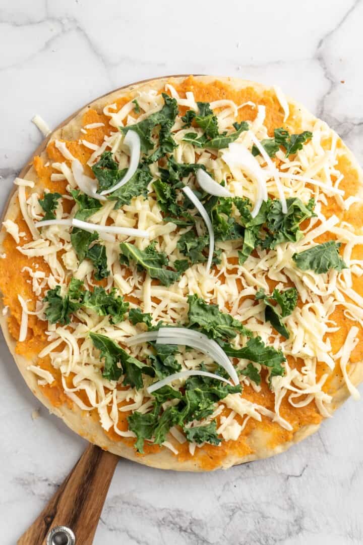 Overhead view of unbaked sweet potato and kale pizza