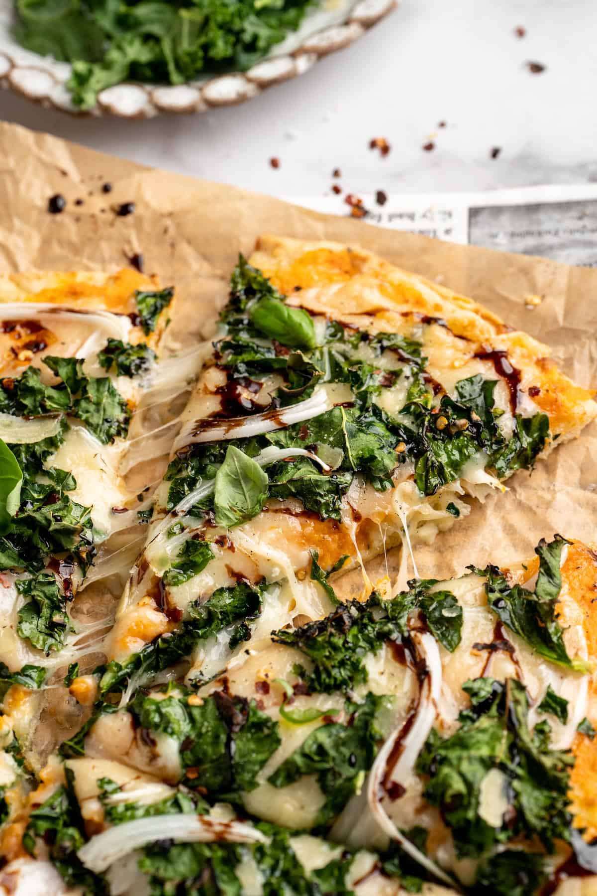 Vegan sweet potato and kale pizza with one slice pulled away slightly