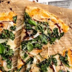 Overhead view of sweet potato and kale pizza with one slice pulled away slightly