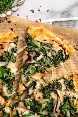 Overhead view of sweet potato and kale pizza with one slice pulled away slightly