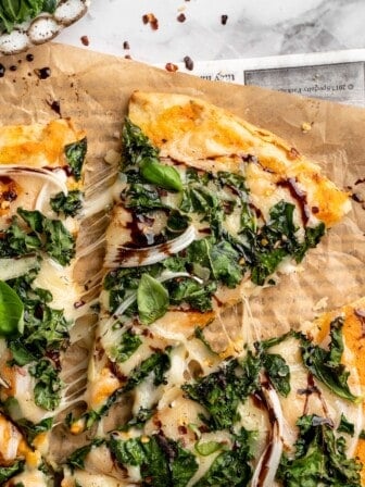 Overhead view of sweet potato and kale pizza with one slice pulled away slightly