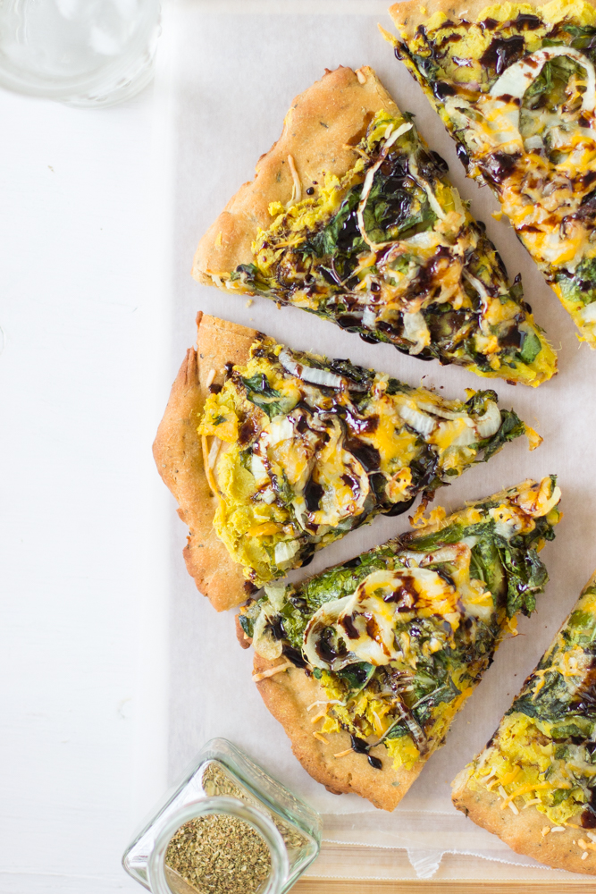 Slices of sweet potato and kale pizza on a white table.