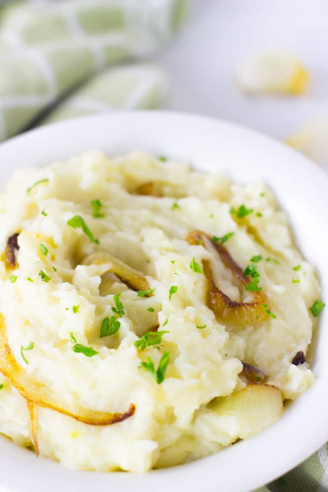 Close up of garlic mashed potatoes in a white pot.