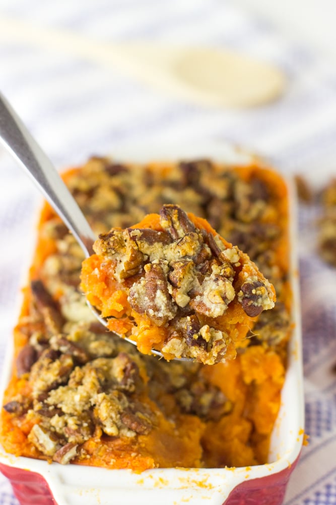 A spoon scooping out sweet potato casserole form a baking dish.