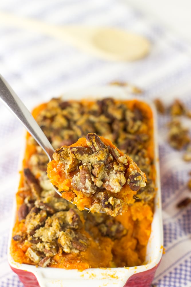 Close up of a spoonful of casserole in front of a baking dish.