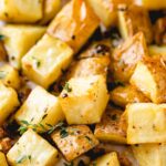 roasted potatoes on a baking sheet with thyme on top