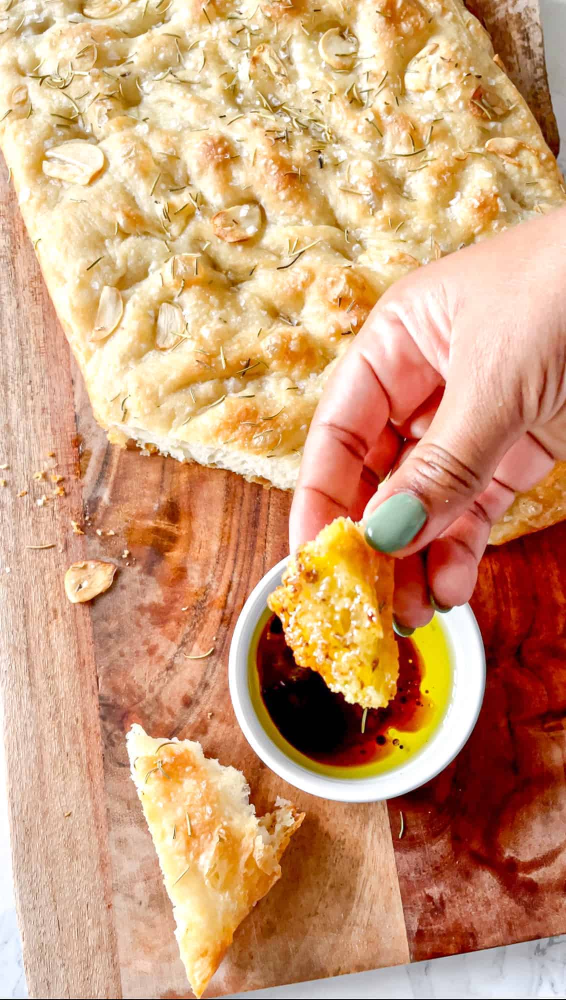 focaccia being dipped into a bowl with olive oil and balsamic vinegar 