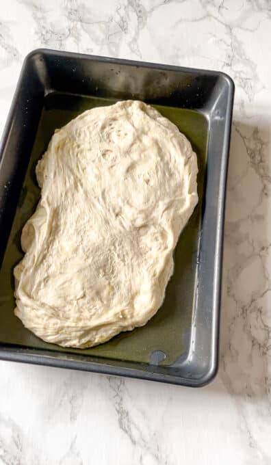 bread dough in an oiled baking pan