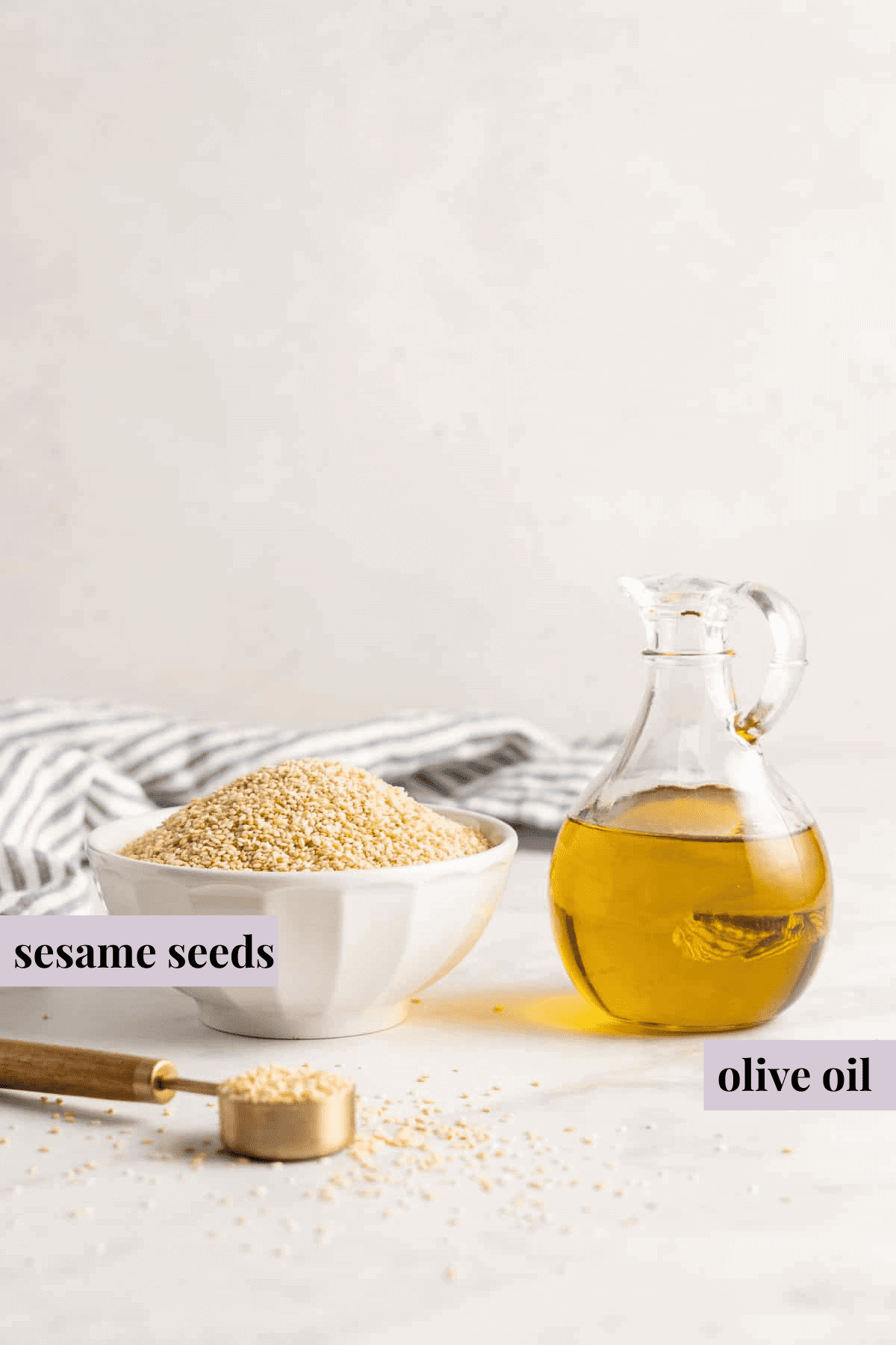 Bowl of sesame seeds and glass pitcher of olive oil