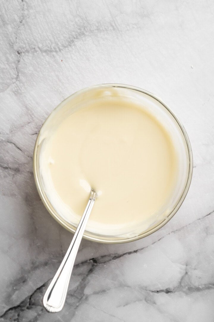 Melted white chocolate in bowl with spoon.