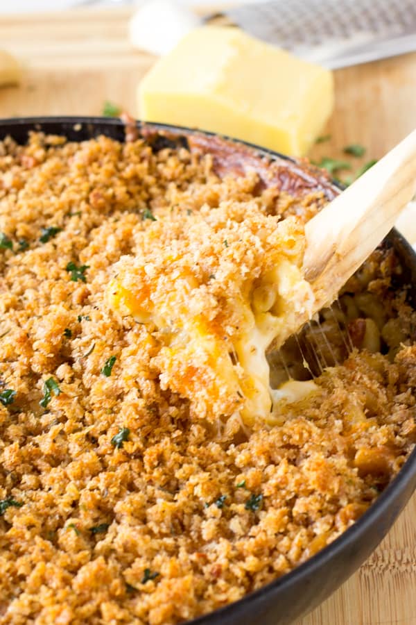 Spoon scooping out baked macaroni and cheese out of a skillet.