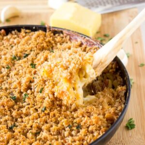 Spoon digging into a skillet of mac and cheese.