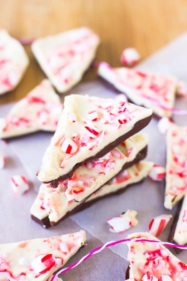 A stack of chocolate bark on parchment with candy canes. 